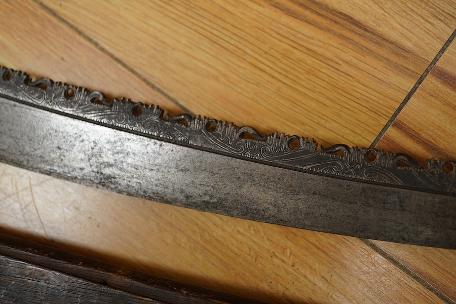 An elaborate Dayak headhunter’s sword Mandau, curved blade with chiselled and engraved back edge, large bone grip carved with protruding teeth, etc. in its wooden scabbard. Condition - good, some age wear.